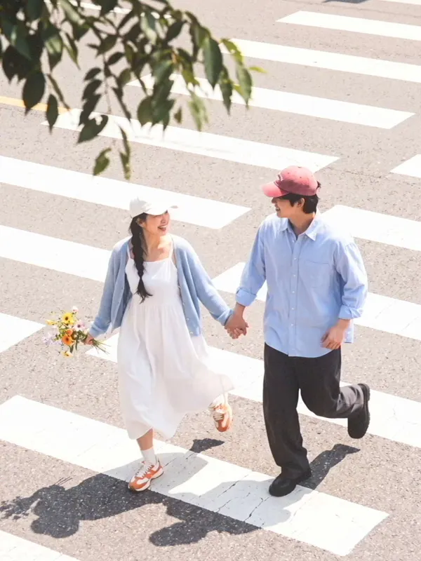 A couple holding hands on a zebra crossing, soft and bright.